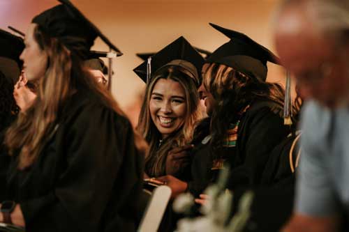 Female graduates smiling in the audience at MGA's Spring 2024 graduation ceremony.